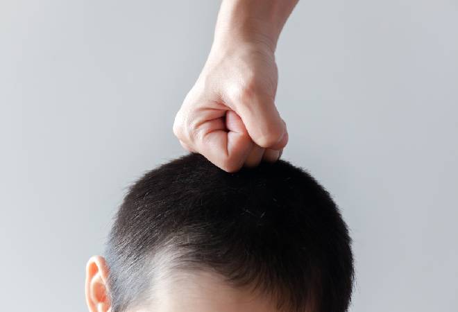 少年の頭に拳を突き立てている画像。