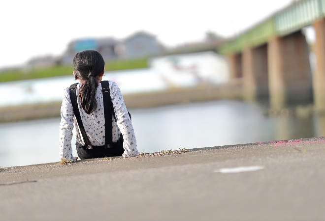 河原に佇む少女の後ろ姿。