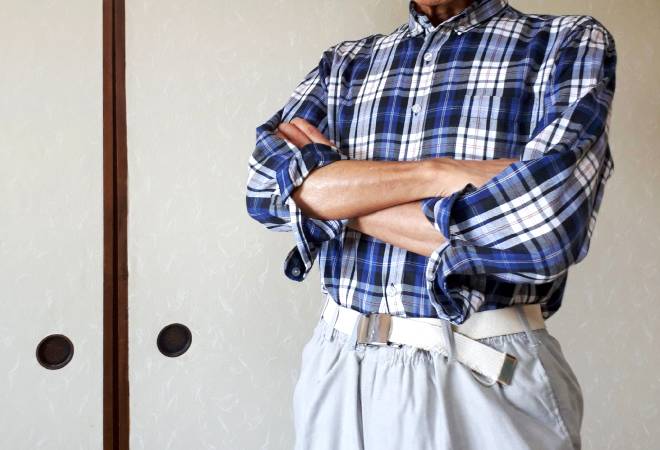 腕を組む高齢男性の姿。