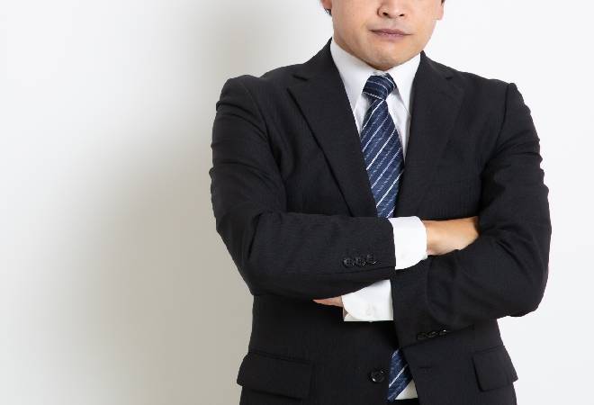 腕を組み怒っている様子のスーツの男性。