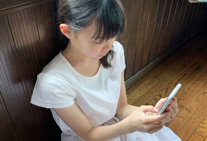 スマホを持って浮かない顔をする小学生。