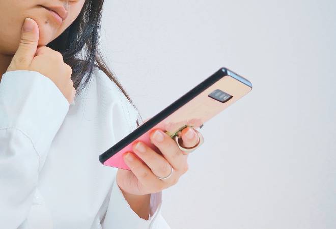 スマホを不安げに見る女性の姿。
